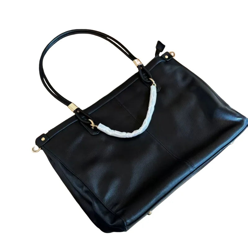 Large leather tote bag with double round handles, gold metal hardware, vertical stitching, and spacious capacity.